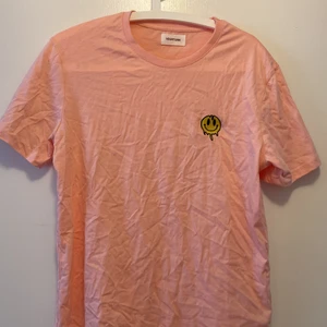 Tshirt - En aprikos/rosa T-shirt från yourturn beställd från junkyard. En broderad emoji på ena sidan. Den är Oversized å passar xs men även lite tajtare på s och m! Aldrig använd!