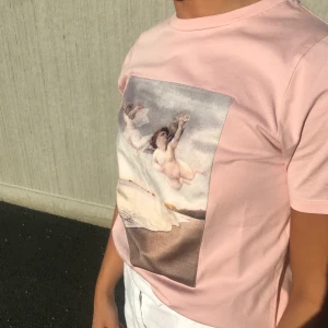 Rosa t-shirt med änglar  -  Rosa t-shirt med ängeltryck från NAKD. Storlek XS. Aldrig använd 