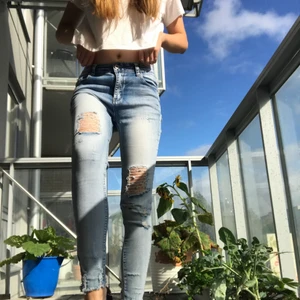 Skinny jeans med hål - Ett par ljusblåa skinny jeans med hål i och fransar längst ner. Materialet är stretchig. Knappen sitter lite lös men jag testade och det utgår ingen fara, den sitter fast. 