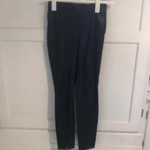 Fusk skinnbyxor från Zara storlek Xs - Byxor i fuskskinn från zara. Smala i modellen och med små slitsar längst ner där fram. Använda men i fint skick.