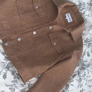 NA-KD jacka - Tänker sälja min bruna jacka då den aldrig kommit till användning har använt den 3h samanlagt. Den är alltså helt ny och oanvänd, i jättefint skick☺️ Den är kort och brun med silvriga knappar. Den är i redigt material och inte sånt tunnt som andra skjortjackor är i, så den passar till hösten och våren exempelvis, 🥰tycker den är fin men den tillhör inte riktigt min stil så hoppas den kan komma till användning hos någon annan intresserad! ✨