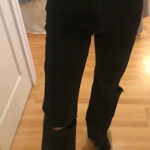Svarta jeans från Carin Wester - Svarta straight leg jeans från Carin Wester med hål på knäna. De har tappat lite svart färg från tvätten och är upp sprätta ner till. Skriv om du är intresserad av att se fler bilder
