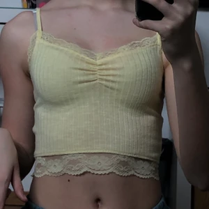 gul topp med spets - jättegulligt ljusgult linne med spetsdetaljer!! säljs pågrund utav att jag inte använder det, och det är nästintill oanvänt. billigt pris pga att jag inte minns vart jag köpte den/hur mycket det kostade :) FRAKT INGÅR EJ I PRISET