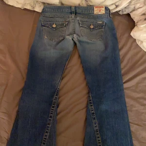 Lågmidjade jeans - Skitsnygga lågmidjade bootcut jeans från True Religion, köpta i somras men inte använt så mkt. Har blivit två hål mellan benen men går att sy ihop. Passar mig bra som är 162 och har stolek XS/S i jeans. Kan både mötas och frakta!❤️