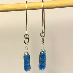Handgjorda örhängen i blått glas och handgjorda örkrokar i fyrkantig silvertråd (Sterlingsilver ca 1 mm). Glasets baksida ger ett silvrigt intryck.