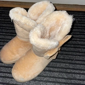 Beiga UGGs med rosett - Knappt använda, bra skick. Inte från UGGs märket vet ej märke tror ”Sports”?? Storlek 39/40 men skulle säga 38 för passar inte mig som har 39/40. Skriv för mer info💞 Frakt tillkommer 66kr. 