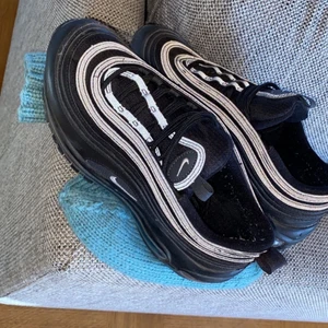 Nike Air Max 97 - Svarta nike air max 97 med reflex. Dom är använda ca 2-3 gånger endast, så är i fint skick och knappt ingådda. Dom är dock otroligt bekväma att gå i. De kostar 1.500 kr där av priset:) Köparen står för frakten! Skokartong saknas tyvärr, men om det önskas lägger jag dom i en annan kartong.