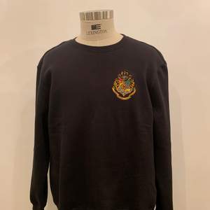Svart tröja i stl L från herravdelningen på H&M som jag själv har broderat Hogwarts märket på. 
