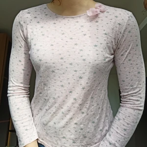 Långärmad Pyjamaströja från Terranova XS - Bomull, mjuk och i bra skick. Passar barn i åldrarna 8-13. Har stjärnmotiv på en rosa bakgrund och en liten rosa rosett på axeln 🌸