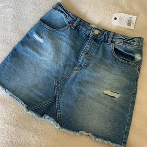 Helt ny kjol i denim  - Kort jeanskjol i storlek 38, liten i storleken så skulle passa dig som är mellan storlek 36/38. Den har slitningar både i fram och i bak. 