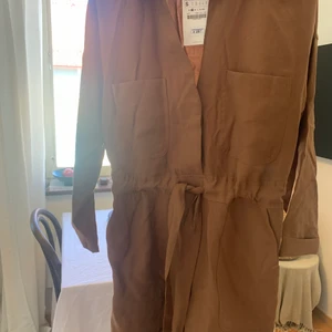 Mörkbrun playsuit från ZARA - Storlek S, oanvänd. Knyte i midjan och vida ben 🥰