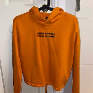 En fin orange hoodie som aldrig har kommit till användning i storlek XS. Det går att dra åt vid nedre delen av hoodien.