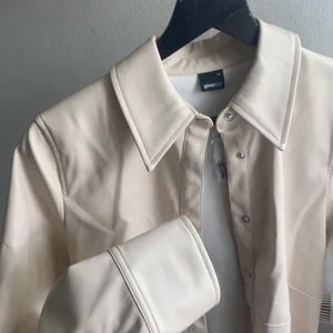 Vit/beige Skinnskjorta - Vit/beige skinnskjorta från GinaTricot. Aldrig använd (pga. fel storlek) med lapp och extra knappar kvar. Storlek 34 oversized. Skriv för fler bilder eller andra frågor. 📦FRAKT INGÅR I PRISET