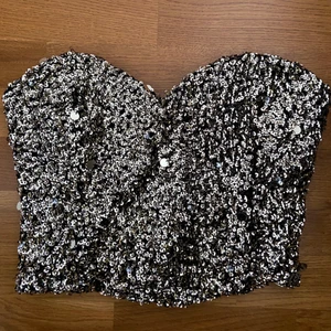 Glitter topp - En guldig glittrig bandeu topp från Gina Tricot. Tröjan består av paljetter som bilderna visar. Spännen i olika storlekar finns bak. Köpare står för frakten!!