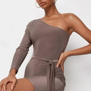 Beige jumpsuit - Helt oanvänd! Beige/brun en ärm jumpsuit/playsuit med bälte i midjan för att framhäva ens former, i slank tyg som är väldig stretchig.  Passar storlek personer som bär S och M                                                