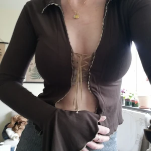 Croptop från NBC strl. M - Helt unik, brun snygg croptop med snörning framtill, klockärm och snygga detaljer, den är strechig och sitter tajt på mig som har s/m helt oanvänd från 90talet går inte att hitta nu. 