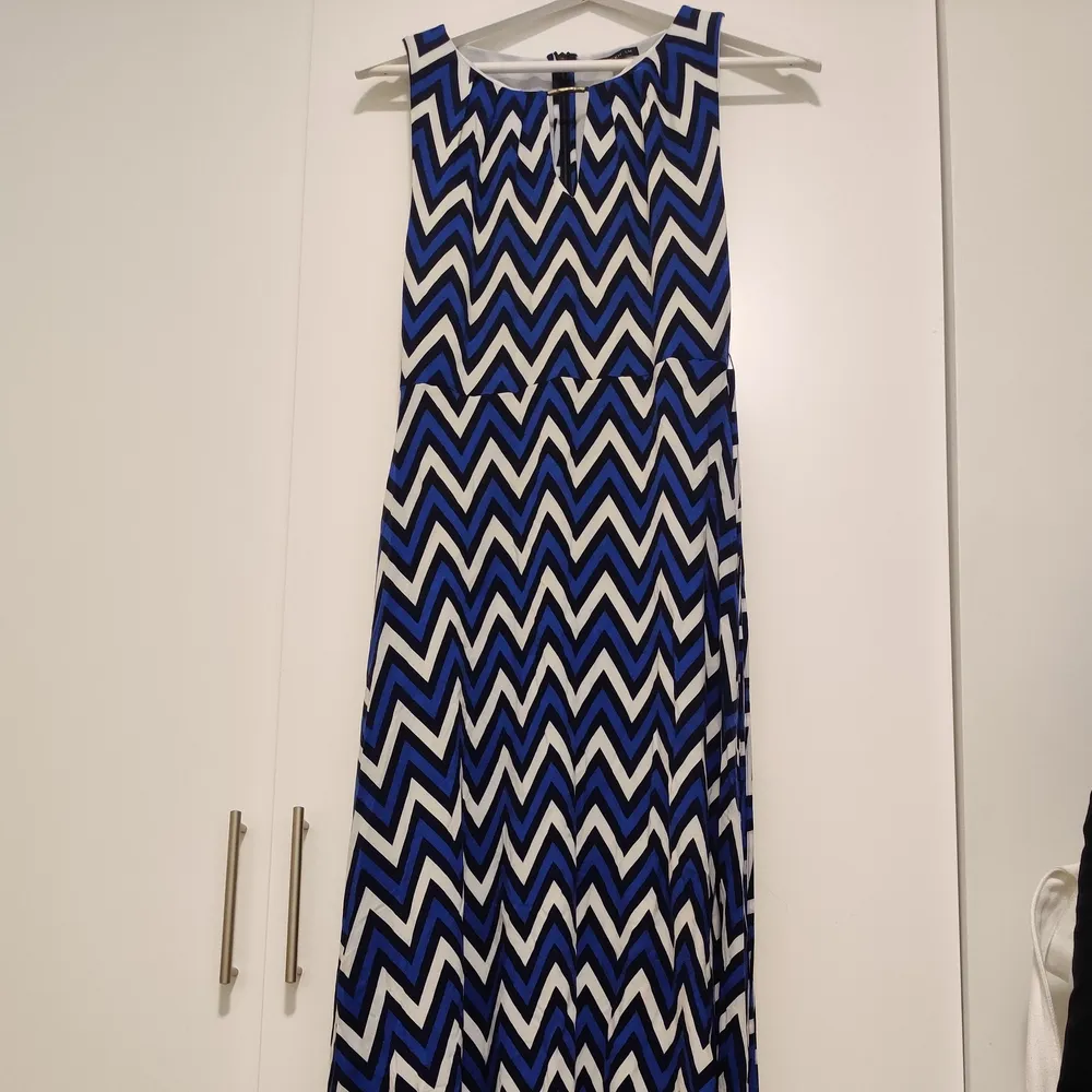 Beautiful and flattering dress from the brand STOCKH LM. Ties in the waist with a matching thin belt with brass/gold detailing and sits very flattering around the waist when tied. Chevron-pattern is expected to come back in style during 2022, and this dress does it really well. Great, heavy fabric in good quality. Brass/gold detailing has some discoloration, and one of the small belt-loops are missing - but otherwise in great condition. . Klänningar.