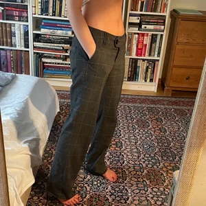 Lågmidjade kostymbyxor  - Gråa, rutiga kostymbyxor! De är låga i midjan och funkar fint med och utan skärp! Säljer pga för stora på mig som är 163cm! De är i storlek 36, men skulle säga att de även passar 38. Sparsamt använda. 
