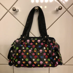 Liten väska  - En liten, charmig och rolig handväska. Ca 25 cm lång och 13 cm hög. En ytterficka på varje kortsida och ett innerfack på insidan. Använd endast ett fåtal gånger.