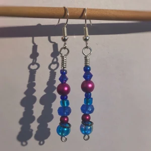 Drömmiga örhängen - Fina långhängande örhängen gjorda med lila och blåa pärlor. Kan fraktas och hämtas upp i Stockholm/Huddinge. Skriv vid frågor!