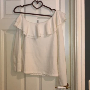 Tröja - Vit tröja med en sveskurning vid axlarna med volang