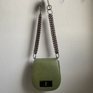 mörkgrön väska - Säljer den här skitsnygga väskan från nakd. Köpt för väldigt länge sen men är sparsamt använd. Supercoola kedjor! Köparen står för frakten 💕 Köptes för 400kr