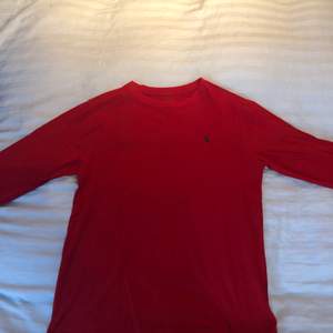 Polo Ralph Lauren tröjan är använd men i bra skick. Den är långärmad och i färgen röd. Tröjan passar för åldrarna 14-16.