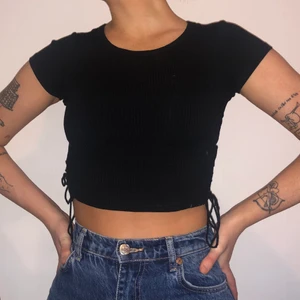  Ribbad crop top med snörning - Superfin svart ribbad crop top med snörning i sidorna. Storlek xs, men passar även small. Använd endast två gånger så toppen är i nyskick!💕
