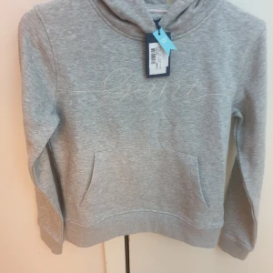 Grå Gant hoodie  - Den är helt ny, har aldrig används. Jag fick den och storleken passade inte mig. Det är därför jag säljer den.