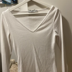 Vit V-ringad topp  - Säljer den här super snygga toppen från NA-KD som jag köpte för 199kr 💕 Säljer för att den inte kommer till användning. Den är i storlek XS men den är väldigt stretchiga så passar upp till storlek M skulle jag säga och är i väldigt bra skick 😊 Hör av dig om du vill ha fler bilder eller annat. Kan mötas upp i Stockholm och betalning sker via Swish pris kan diskuteras 