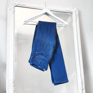 blå Wrangler Jeans 25/34 - Fina Wrangler jeans, i mycket gott skick. Strl: W:25 L:34. Skönt stretch material, sluts igen med dragkedja och knäpp framtill. Två framfickor och två baktill. Tight modell/stuprör. Använda vid 2-3 tillfällen endast. Nästintill som nya!