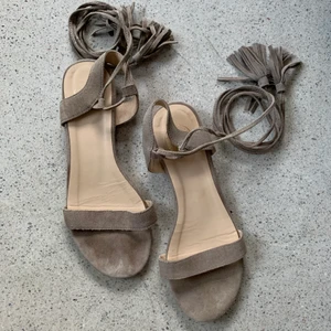 Mocka sandaler i beige, stl 41 - Ett par milt använda sandaler från Indiska. Beige mocka med långa snören som går att knyta runt benet. Stl 41. Använda fåtal gånger. Köparen står för frakt.