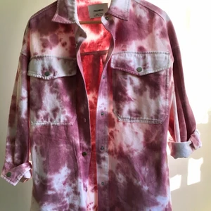 Skjortjacka - Sorlek xs, oversized i nyskick, batikmönster i vitt och rosa. Tryckknappar i metall. Två fickor fram och två sidofickor. Rygglängden är 78 cm. Stor i storleken. Köpt på rea och aldrig använd. 