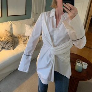 Adoore, skjorta, strl M - Storlek M, men skulle säga att den är mer en S. Adoore brukar upplevas som mer figurnära. Assymetrisk, svarta detaljer runt ärmalutet. Har inte steamat bandet så noga på bilden.