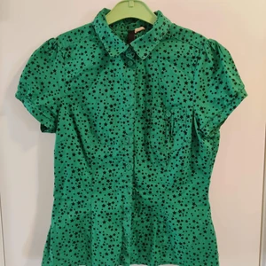 Kortärmad blus - Färgstark blus med svarta stjärnor. Bröstficka på vänster sida.