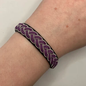 Tenntrådsarmband  - Handgjort Tenntrådsarmband, svart med lila fläta. Materialet armbandet är gjort i är lammskinn, och flätan är gjort i tenntråd. Armbandet kan hålla i flera år. Om du har någon fråga kan du gärna skriva en kommentar eller meddela mig.
