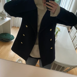 Marinblå kort kappa - Marinblå kort kappa (skepparkavaj) med guldiga knappar. Från Benetton, inköpt i Italien. Storlek 38/M, upplevs dock något liten i storleken och passar därför en S bra. Kappan är i princip aldrig använd och är därför i nyskick. Inköpt för ca 1800kr.