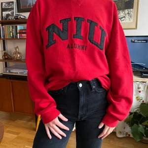 Röd sweatshirt, storlek L med broderat tryck i svart. 