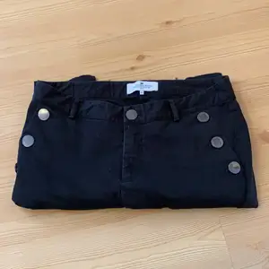 Svarta jeans med knappar på sidorna i storlek 42. Inga skavanker dragkedja vid fötterna. 