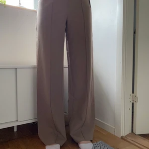 Kostymbyxor från NA-KD storlek 34 - Säljer ett par kostymliknande byxor med vida ben och söm då dem är för långa. Personen på bilden är 168 cm lång. De är aldrig använda och har prislapp kvar. Byxorna är i storlek 34. Nypris är 350kr och jag säljer dem för 250 + frakt.