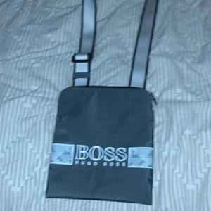 Hugo Boss Axelväska - Väskan är köpt i våras på boozt, är använd 5-6 ggr. Säljer då jag känner att jag inte har nån användning för väskan. 800kr för väskan man kan gå ner i pris vid snabb affär. Det står 450kr för väskan men kunde ej ha högre pris, det är därför jag har skrivit att priset är 800kr.