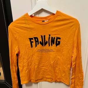 Orange långärmad från H&M - En pumpaorange långärmad topp med svart text som tryck, använd ett fåtal gånger 