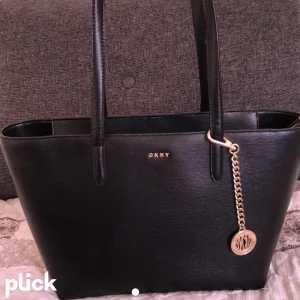 DKNY handväska - En fin handväska i äkta koläder. Jag köpte den förra sommaren för 2045 kr men den är knappt använd.