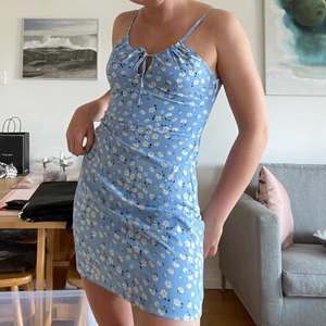 Klänning - Blå klänning med söta blommor och knytning. Säljer då den är lite för liten och har aldrig använt den utan bara provat. Den är i strl M men jag brukar ha M och tycker den är för liten. 