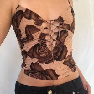 Brun y2k topp - Brun topp från opera clothing! Smyckad med glitterdetaljer och snörning mellan bysten. Defektfri. Visas på storlek S. Köpare står för frakt. Högsta bud 240kr! Avslutas 20/6-21 21:30. KÖP DIREKT FÖR 300!