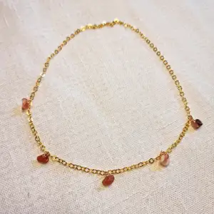 Guldfärgat halsband med små kristaller av karneol 💎 Kedjan är ca 40 cm, och passformen går att justera. Skickas i vadderat kuvert via postnord. 