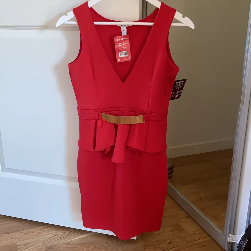 Röd klänning med gulddetaljer från Nelly, aldrig använd! Prislappen är kvar.  ✨ Köpt för 100 kr, säljer för ENDAST 49 KR RABATTERAD PRIS! . Klänningar.