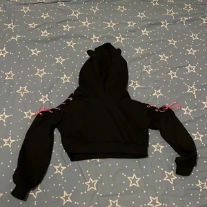 Emo hoodie  - En emo/alternativ hoodie. Kattöron på luvan. Tråd på ärmarna som man kan byta sa hon i butiken. Den är int jättetjock i materialet så man kan ha den på vårennoch sommaren. Det är en magtröja som går över naveln. Köpte denna för 500kr på c.u.m clubwear i Stockholm. Säljer denna för att det inte är min stil längre. Använde den ungefär 1 gång. Storlek M men jag är XS S och den passar perfekt på mig. ⚠️ på bilden där jag har tröjan på har jag ett svart linne under. 