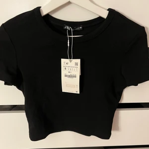 Svart t-shirt stl S från zara - Säljer denna cropade t-shirt från zara, helt oanvänd med prislappen kvar. Köparen står för frakten 