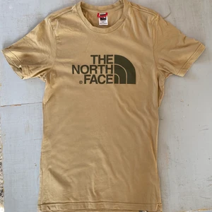 The North Face T-Shirt - En ljusbrun/beige t-Shirt från the north face i väldigt bra skick. Säljer då den inte kommer till användning längre